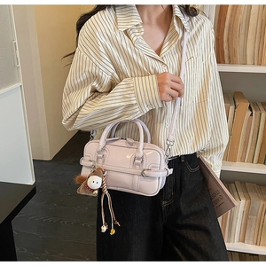 Detail of light purple glossy handbag with cute donkey charm and adjustable strap