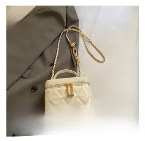 Dettaglio borsa trapuntata crema con tracolla a catena oro e ciondolo zip sferico