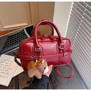 Detailed shot of red glossy patent leather bowling bag with brown plush horse charm