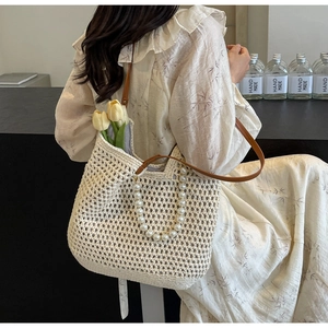 Detail of hand-woven crochet tote with large pearl handle and brown leather strap