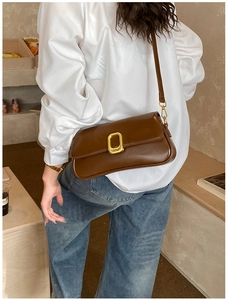 Close-up of brown leather crossbody bag featuring a sleek gold metal buckle and strap hooks