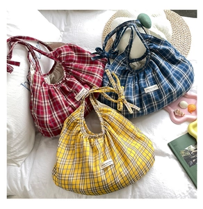 Detailed view of plaid tote bags in red, blue, and yellow with stylish pleated texture