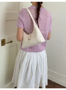 Detail of ivory leather hobo bag with a vertical metal buckle strap on a model