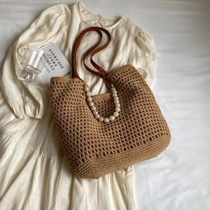 Detail showing the straw tote bag texture with elegant pearl handle and leather shoulder strap