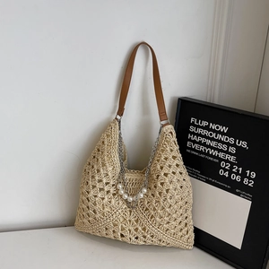 Detail of hand-woven beige tote bag featuring pearl ornaments and silver chain link