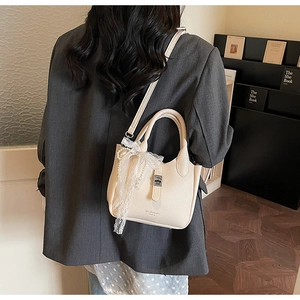 Chic beige bucket bag with pearl lace pendant and metallic buckle in a crossbody style