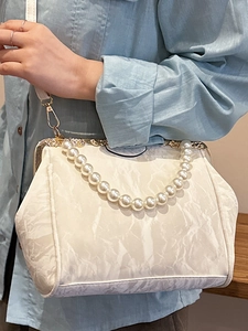 Elegant off-white shell handbag with oversized pearl handle and metal clip closure