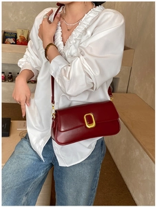 Detail of burgundy leather square bag with vintage gold buckle and smooth matte finish