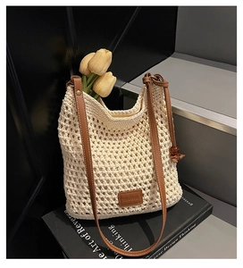 Detailed close-up of woven cream tote bag with brown leather strap and brand patch