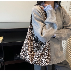 Detailed shot of a large leopard print canvas tote bag worn on shoulder for daily commute