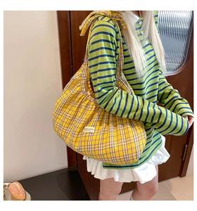 Detail of yellow checkered fabric tote bag featuring a large bow and soft cotton texture