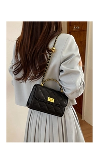 Schwarze Stepptasche mit goldener Kette, getragen von einem Modell von hinten