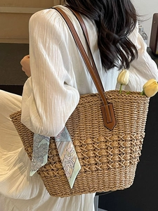 Large woven straw tote bag with brown leather straps and floral scarf for beach vacation