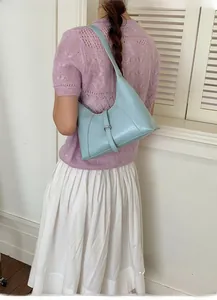 Close-up of a light blue crescent shoulder bag with silver buckle worn by a model