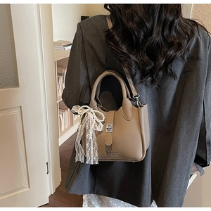 Detail of lychee pattern leather bucket bag with elegant pearl lace bow charm