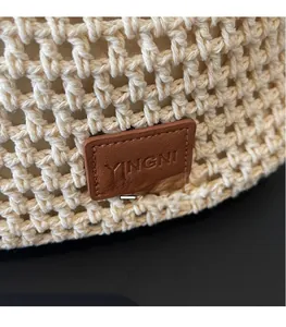 Close-up of beige woven texture featuring a brown leather YINGNI brand logo patch