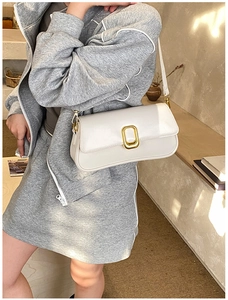 Detail view of white leather crossbody bag with elegant gold metal buckle on flap