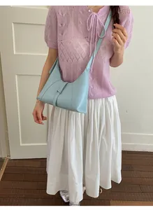 Detail of light blue leather crescent underarm bag with silver buckle on a casual model