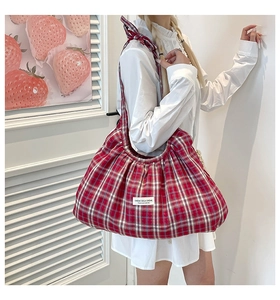 Detail view of red checkered tote bag featuring pleated cloud shape and woven label