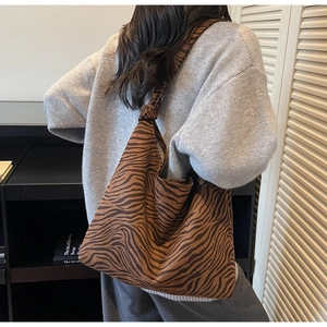 Detail showing zebra print tote bag with knotted shoulder strap worn by a model