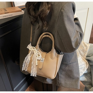 Detail of camel bucket bag showing textured lychee leather and lace pearl charm