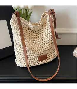 Detailed shot of hand-woven straw bucket bag with brown leather strap and brand label