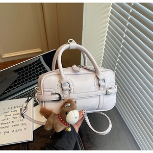 Detail of elegant beige crossbody bag with a cute pony charm and slim leather strap