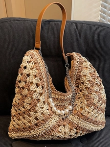 Large woven straw shoulder tote bag with faux pearl chain decor and brown leather straps