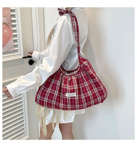 Detail of red plaid pleated tote bag with bow shoulder strap and brand label