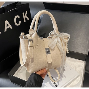 Detail of off-white lychee grain leather bucket bag with pearl lace bow charm