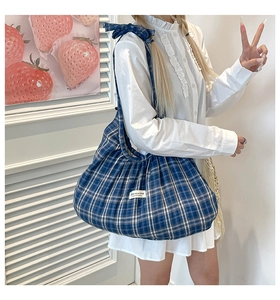 Blue checkered tote bag detail featuring a bow shoulder strap and brand label