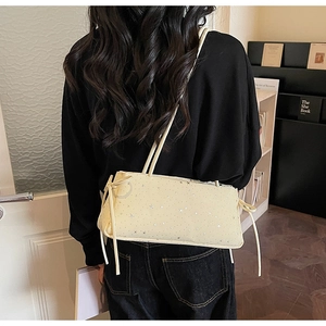 Detail of star-patterned beige shoulder bag featuring side drawstrings and bow accents