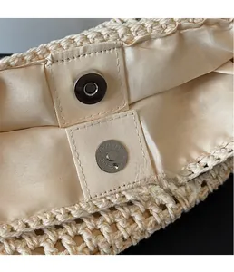 Detailed macro view of silver magnetic buckle and woven fabric lining on beige tote bag