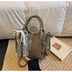 Detail of taupe leather bucket bag with silver twist lock and pearl pendant decoration