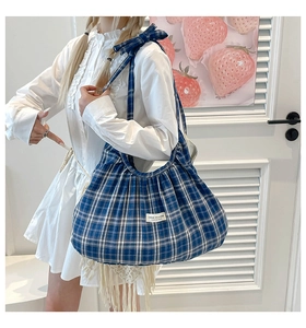 Detail of blue and white checkered shoulder bag with pleated texture and bow strap