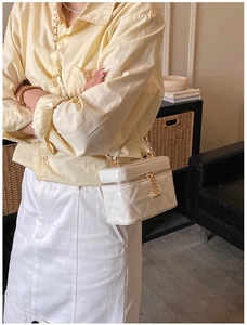 Dettaglio della trama trapuntata bianca e dell'elegante catena dorata sulla borsa a mano