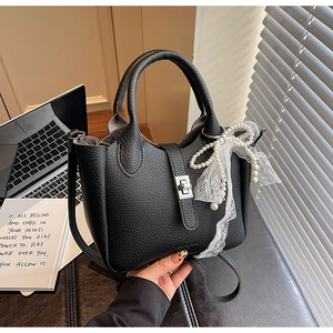 Detail of black pebbled leather tote featuring silver twist lock and pearl lace charm
