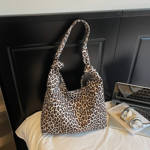 Close-up of leopard print tote bag featuring a stylish knotted strap detail on the bed