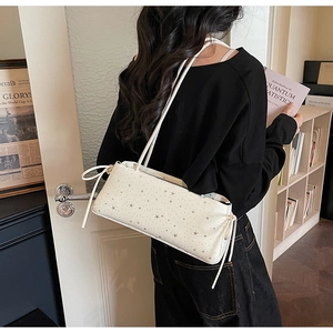 Detail of white star print shoulder bag with elegant side drawstring bow and thin straps