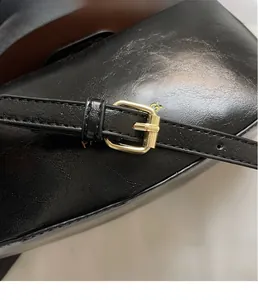 Detail close-up of premium black leather bag featuring an elegant gold metal buckle closure