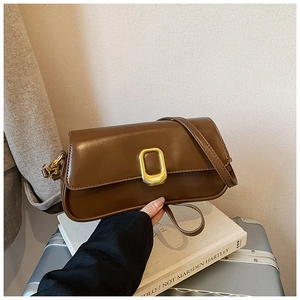 Detail view of brown leather shoulder bag with vintage gold buckle and smooth finish