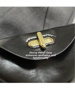 Detail of a polished gold-plated metal twist lock on a black leather commuter handbag