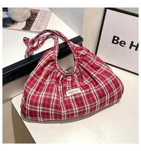 Close-up of red and white checkered fabric tote bag with pleated texture and brand tag