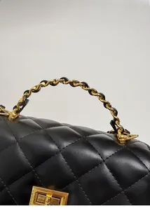 Detailansicht aus schwarzem gestepptem Leder mit goldener Kette und Drehverschluss