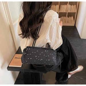 Detail of black crossbody bag with white star patterns and decorative drawstrings