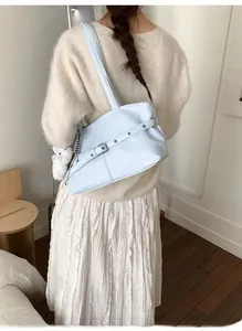 Détail d'un sac cabas bleu clair avec boucle et pendentif en peluche porté par le modèle