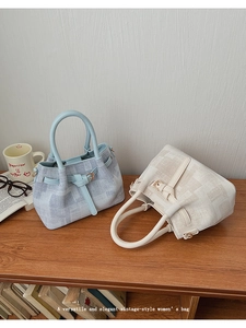 Detail of light blue and beige woven bucket bags with leather handles on a desktop