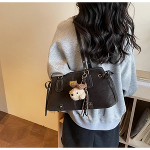Detail of dark brown vintage shoulder bag with matte finish and cute bear pendant