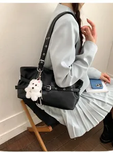 Détail du sac cabas en cuir noir avec bandoulière à œillets et breloque chien
