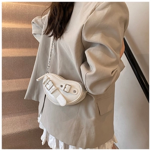 Détail du sac à bandoulière crème en forme de cœur avec chaîne argentée et sangle